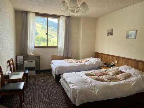 una camera d'albergo con due letti e una finestra di 苗場ロッヂ丘 a Yuzawa