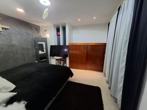 a bedroom with a black bed and a television at suites vergel terraza in Orizaba