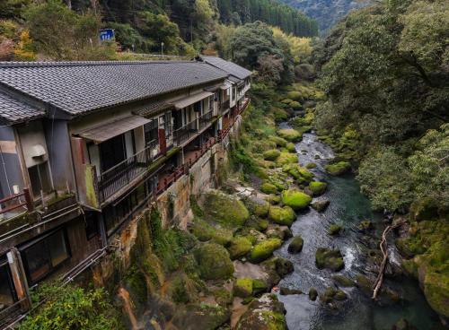 a river in front of a building next to a river at 天然温泉旅館 繁花荘せせらぎ in Kirishima