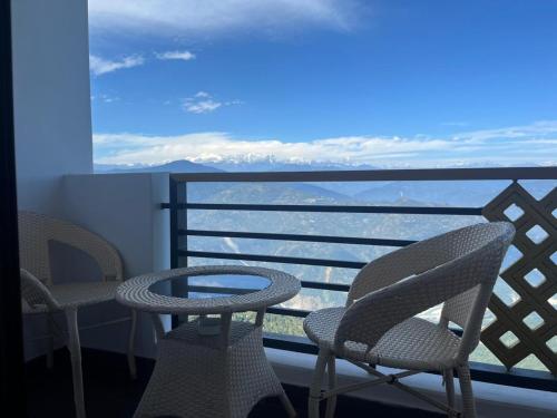 due sedie e un tavolo su un balcone con vista di Delohighs a Kalimpong