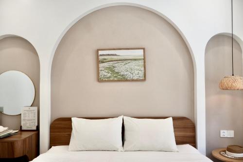 una camera da letto con un arco sopra un letto con cuscini bianchi di Mê Stay Cat Ba a Cat Ba