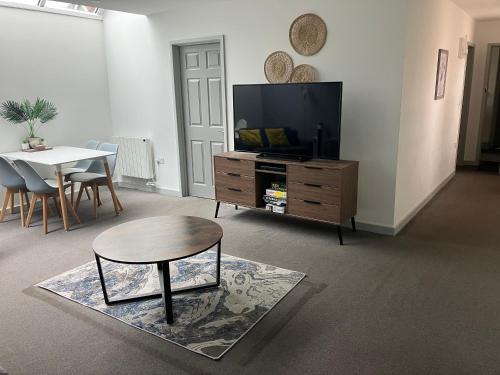 a living room with a table and a tv at Lancing Apartments - Spacious 2 Bed - Sleeps 6 - Burnham Village in Slough
