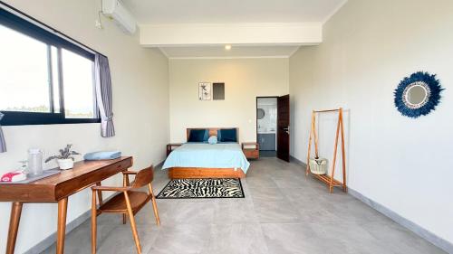 a bedroom with a bed and a desk and a table at Ocean Daze Villa Yehsumbul in Jembrana