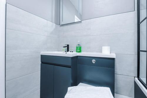 a bathroom with a blue sink and a mirror at 2 BDR House By Eason Stays Short Lets Stockport in Stockport