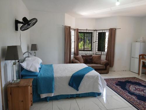 a bedroom with a blue and white bed and a couch at Cambridge Heights Guest House in Port Maria