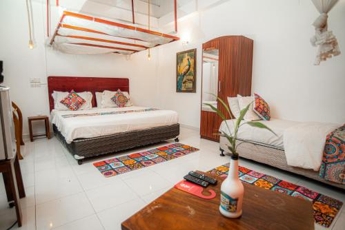 a bedroom with two beds and a table with a vase at Prime Time Hotel in Unawatuna