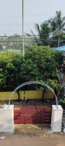 a red gate in front of a yellow building at punartham homestay in Kovalam