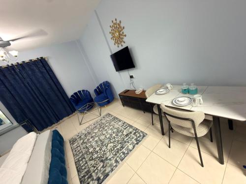 a living room with a table and chairs and a television at spacious fully furnished studio apartment in Emirates cluster in Dubai