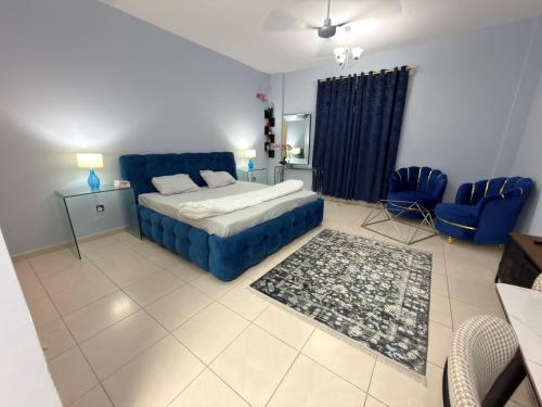 a bedroom with a bed and a blue couch and chairs at spacious fully furnished studio apartment in Emirates cluster in Dubai