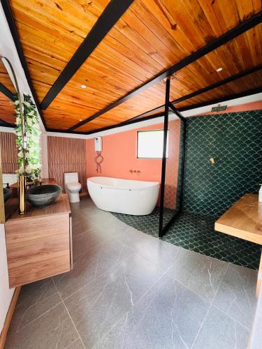 a bathroom with a white tub and a wooden ceiling at La Boca del Lagarto Lodge in Cucunubá