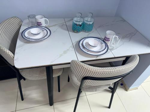 a white table with two chairs and plates and mugs at spacious fully furnished studio apartment in Emirates cluster in Dubai