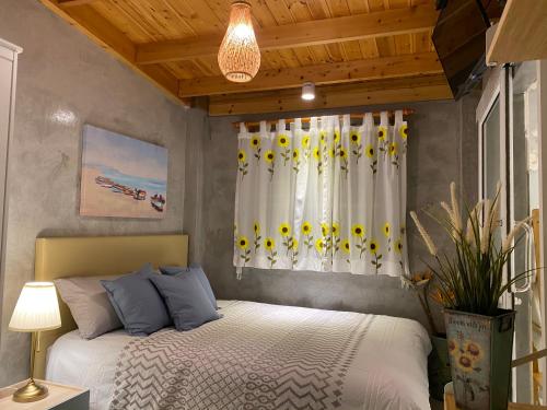 a bedroom with a bed and a window with yellow flowers at Beach Gardens Thasala 1 Bed in Ban Pak Nam Pak Duat