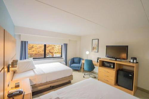 a hotel room with two beds and a flat screen tv at Elimwood Hotel, a Ramada by Wyndham in Maryland Heights