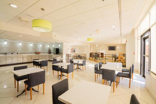 a restaurant with tables and chairs and a kitchen at Elimwood Hotel, a Ramada by Wyndham in Maryland Heights