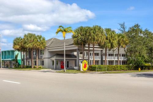 a building with palm trees in front of a street at Super 8 Motel by Wyndham near Fort Lauderdale Arpt in Dania Beach