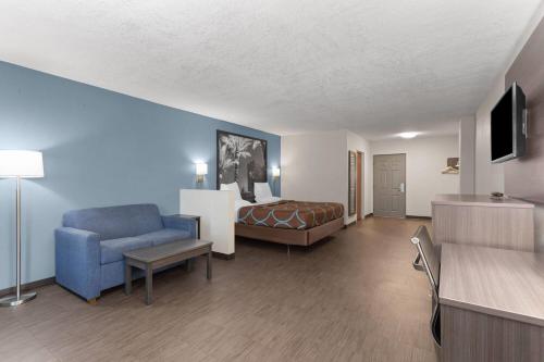 a hotel room with a bed and a blue chair at Super 8 Motel by Wyndham near Fort Lauderdale Arpt in Dania Beach