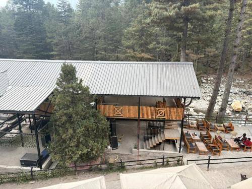 un edificio con un ponte con panchine e un albero di Hotel Purnima by smugglers hotels a Kasol