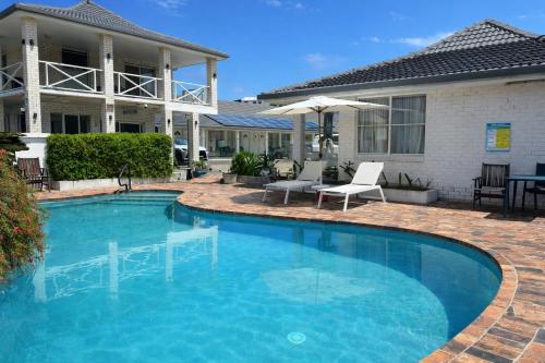 una piscina davanti a una casa di Cooks Endeavour Motor Inn a Tweed Heads