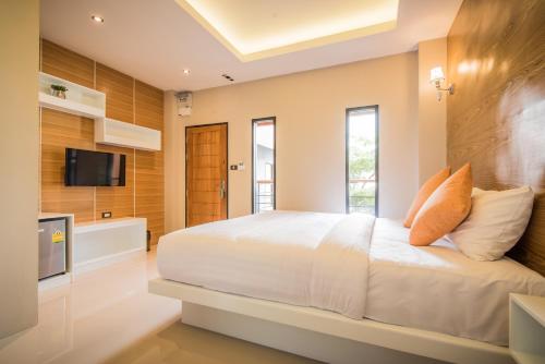 1 dormitorio con 1 cama blanca y TV en Le Terrarium Bed & Sleep Chiang Rai, en Chiang Rai