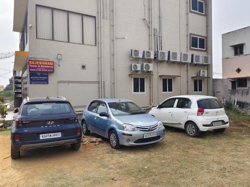 drie auto's geparkeerd voor een gebouw bij Rajeshwari Tower & Residency in Tiruvannamalai