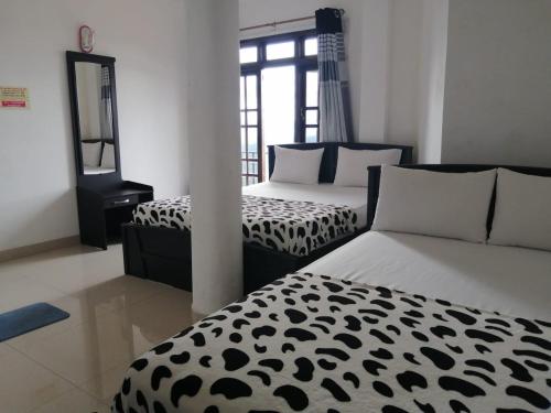 a bedroom with two beds with black and white sheets at Mystik Muthu View Haputale in Haputale