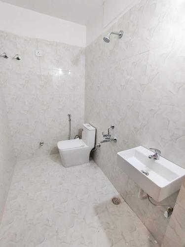 a white bathroom with a toilet and a sink at Soni's Mansion-100m from Khajuraho Temples in Khajurāho