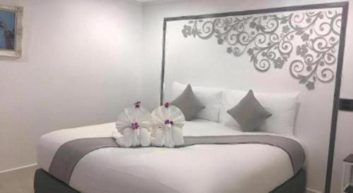 een slaapkamer met een wit bed met 2 bloemen erop bij white house in Phangnga