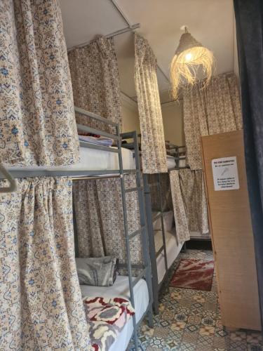 a room with bunk beds with curtains and a chandelier at Hostel Laksour in Marrakesh