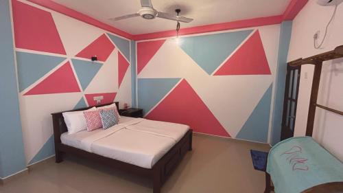 a bedroom with a colorful wall with a bed and a chair at Divas Hostels in Ahangama