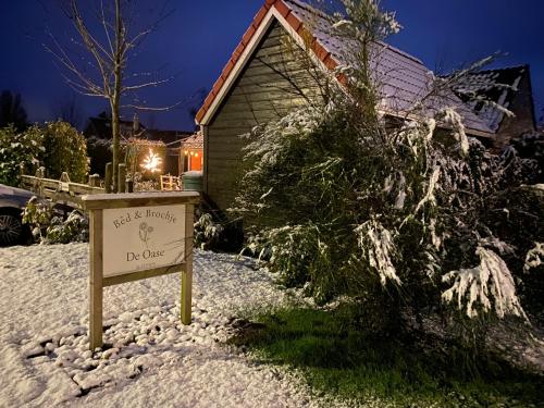 a sign in the snow in front of a house at Bed en Brochje De Oase in Sweagerbosk