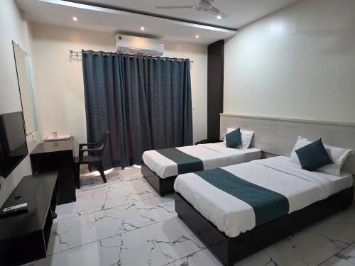 a hotel room with two beds and a desk at Hotel Space Comfort Inn in Karmād