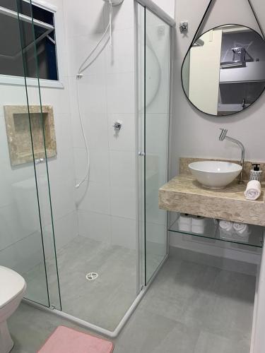 a bathroom with a glass shower and a sink at Lua nova Studio I in Caraguatatuba