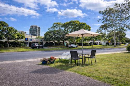 un tavolo e delle sedie sotto un ombrellone sul ciglio della strada di Cooks Endeavour Motor Inn a Tweed Heads