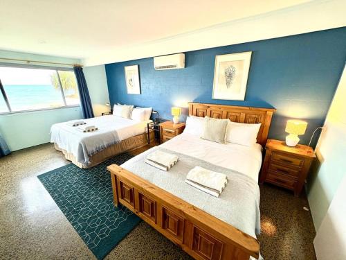 a bedroom with two beds and a blue wall at Driftwood in Bargara