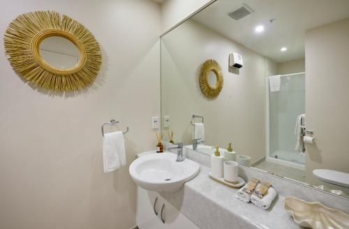 a white bathroom with a sink and a mirror at Beaumont Apartments in Mount Maunganui