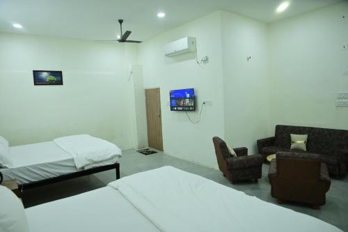 a room with two beds a chair and a tv at The Mapple Stay in Jodhpur