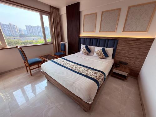 ein Hotelzimmer mit einem Bett und einem großen Fenster in der Unterkunft Hotel Kushala Grand, Dombivali in Mangrul