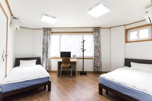 1 dormitorio con 2 camas y escritorio con ordenador en Kory Guesthouse, en Seúl
