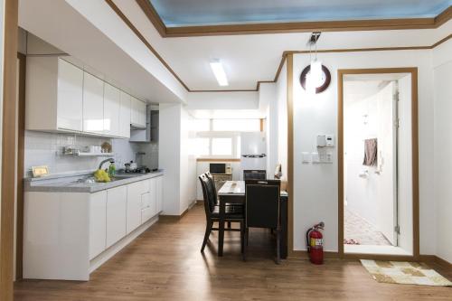 a kitchen with white cabinets and a table and chairs at Kory Guesthouse in Seoul