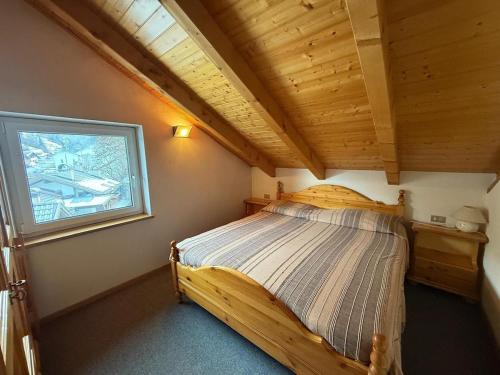 a bedroom with a wooden bed in a room with a window at Casa di Lilly in Moena