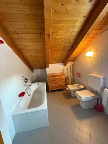a bathroom with two toilets and a tub and a sink at Casa di Lilly in Moena