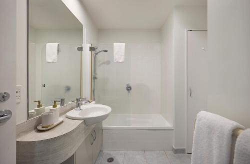 ein weißes Badezimmer mit Waschbecken und Dusche in der Unterkunft Beaumont Apartments in Mount Maunganui