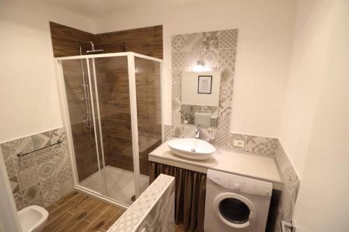 a bathroom with a shower and a sink and a washing machine at Toledo Boutique Studio Apartments in Naples