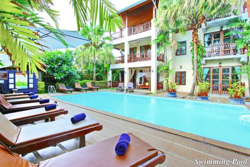 a hotel swimming pool with lounge chairs and a hotel at Shewe Wana Suite Resort in Chiang Mai