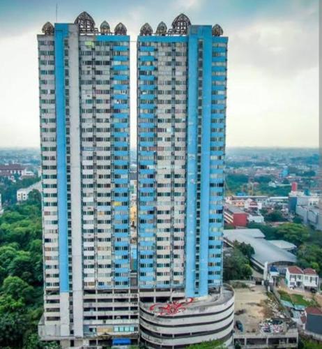 a tall blue and white building in a city at Saladin Guest House in Parungmalela