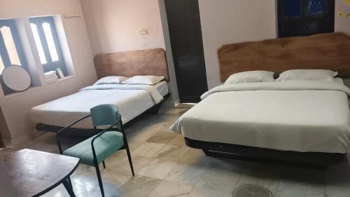 twee bedden in een kamer met een tafel en stoelen bij Hotel Downtown in Jodhpur