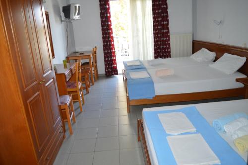 a hotel room with two beds and a table and chairs at Galanis Studios and Apartments in Platamonas