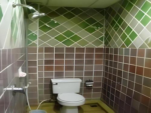 un bagno con un WC e una parete piastrellata verde e marrone di Fah Place Hotel a Nan