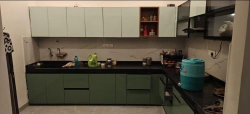 a kitchen with green cabinets and a black counter top at Full villa welcome for you in Jaipur
