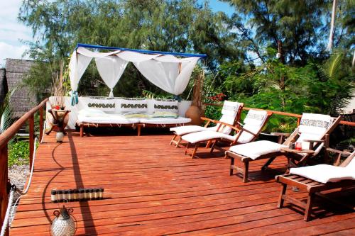 a wooden deck with chairs and a couch on it at Baia Sonambula in Praia do Tofo